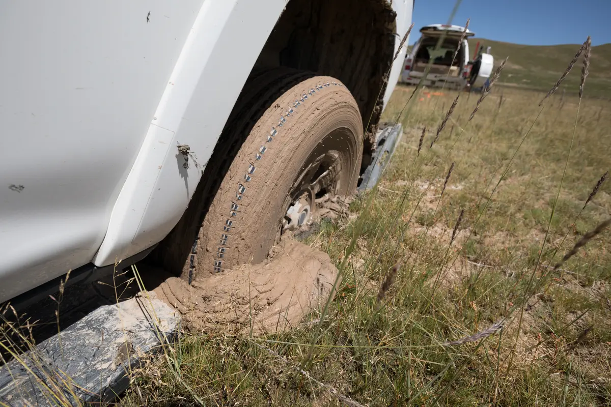 Vehicle wheel stuck deep in mud in a field