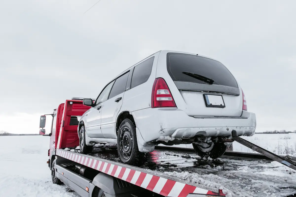 Car loaded on a flatbed recovery truck in winter snow